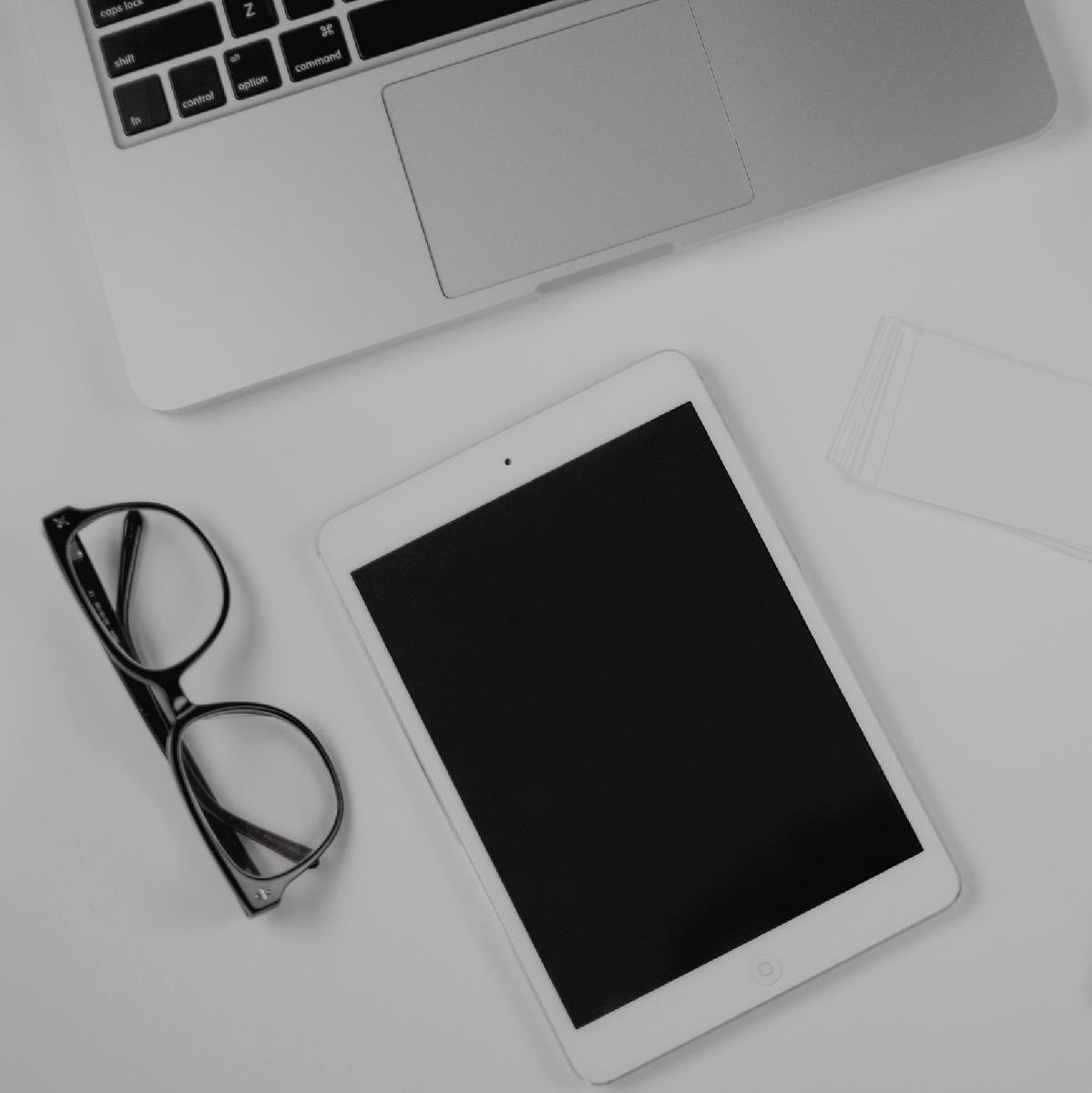 Glasses with an ipad and macbook pro on a table